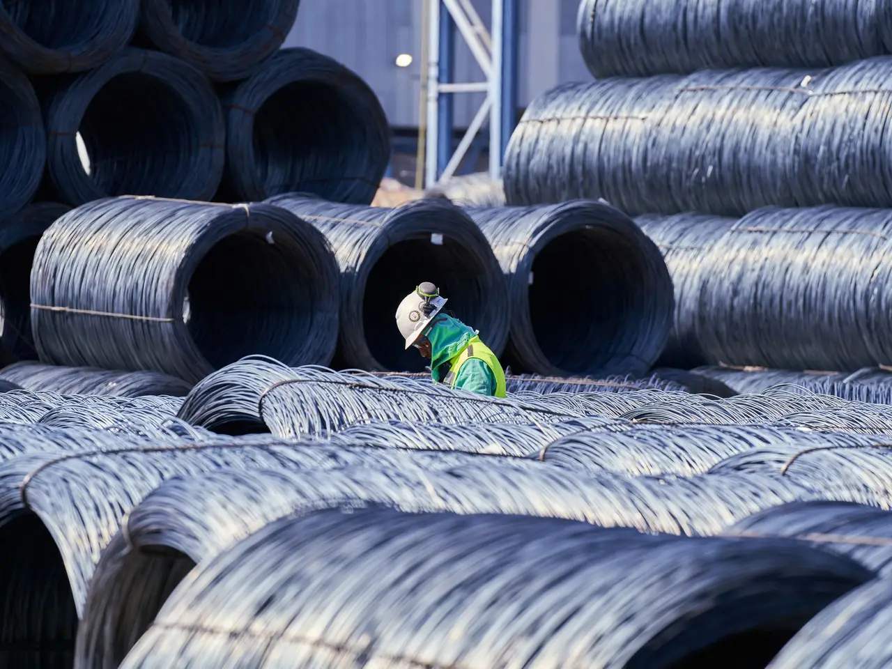 Wire coils in a mill yard, with an operator checking a bundle